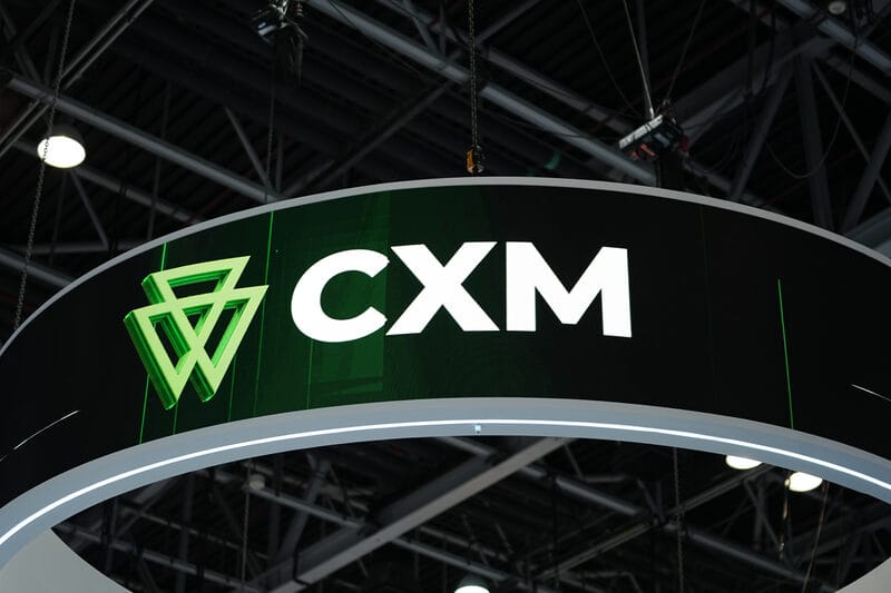 Көрме стендінің тақырыпшасындағы CXM логотипі